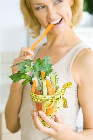 simsearch:695-03378760,k - Woman biting into carrot, holding glass full of vegetables tied with measuring tape Foto de stock - Sin royalties Premium, Código: 695-03378755