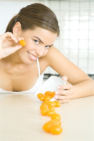 decollete - Young woman spilling dish of cherry tomatoes, smiling at camera Stock Photo - Premium Royalty-Free, Code: 695-03378758