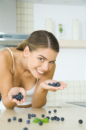 simsearch:695-03378760,k - Woman in kitchen, holding handfuls of blueberries, smiling at camera Foto de stock - Sin royalties Premium, Código: 695-03378760