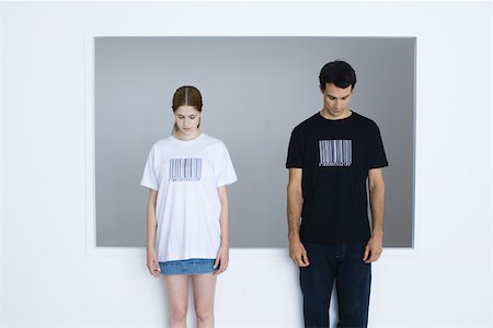 Two young adults wearing tee-shirts printed with bar codes, both looking down Stock Photo - Premium Royalty-Free, Code: 695-03378784