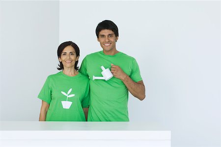 senior man gardener - Man holding watering can, standing beside woman wearing tee-shirt printed with plant graphic, portrait Stock Photo - Premium Royalty-Free, Code: 695-03378790