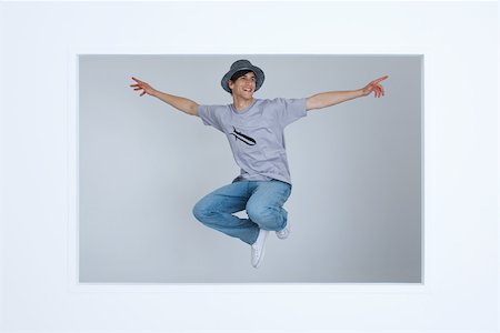 studio graphic - Young man wearing tee-shirt with bomb graphic, jumping in midair, arms outstretched Stock Photo - Premium Royalty-Free, Code: 695-03378801