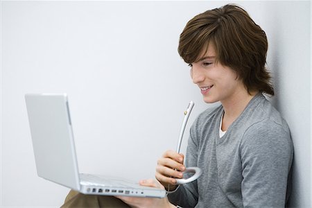 Young man looking at laptop computer, speaking into microphone, side view Stock Photo - Premium Royalty-Free, Code: 695-03378922