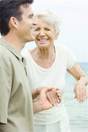 Senior woman and adult son holding hands, laughing, eyes closed Stock Photo - Premium Royalty-Free, Code: 695-03378993