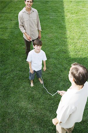 Boy playing jump rope with two men, smiling at camera Stock Photo - Premium Royalty-Free, Code: 695-03379007