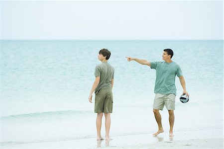 simsearch:696-03395430,k - Father and teen son at the beach, man holding ball and pointing, both looking away Foto de stock - Royalty Free Premium, Número: 695-03379003