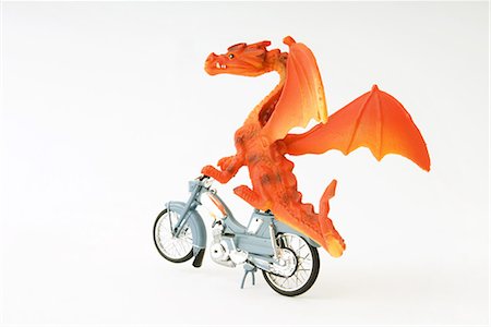 riding a bike funny pic - Toy dragon riding motorbike Stock Photo - Premium Royalty-Free, Code: 695-03379060