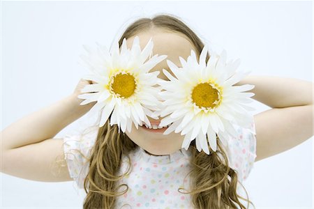 Little girl holding gerbera daisies in front of eyes, smiling, portrait Stock Photo - Premium Royalty-Free, Code: 695-03379076