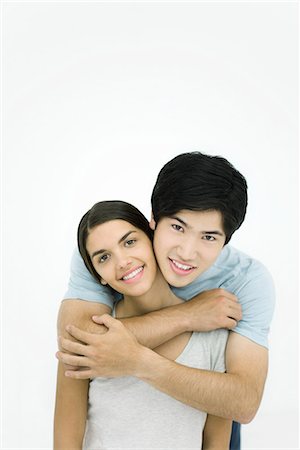 simsearch:695-03390135,k - Jeune couple homme femme embrassant par-derrière, souriant à la caméra, portrait Photographie de stock - Premium Libres de Droits, Code: 695-03379116