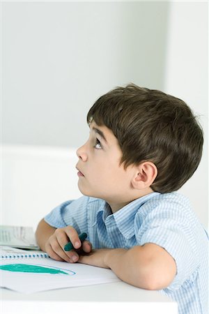 simsearch:695-03380358,k - Little boy sitting at table, holding crayon, looking up Foto de stock - Royalty Free Premium, Número: 695-03379176