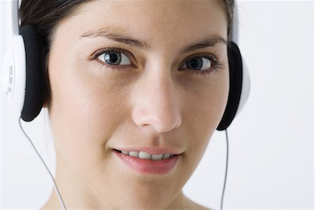 simsearch:633-02128680,k - Young woman listening to headphones, looking at camera, close-up Stock Photo - Premium Royalty-Free, Code: 695-03379170