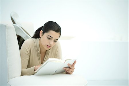 simsearch:695-03377120,k - Young woman lying on couch, reading book Foto de stock - Royalty Free Premium, Número: 695-03379194