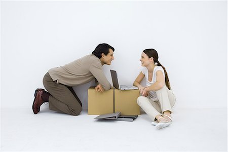 simsearch:695-03380090,k - Couple sitting at makeshift desk with laptop computer between them, smiling at each other Stock Photo - Premium Royalty-Free, Code: 695-03379214