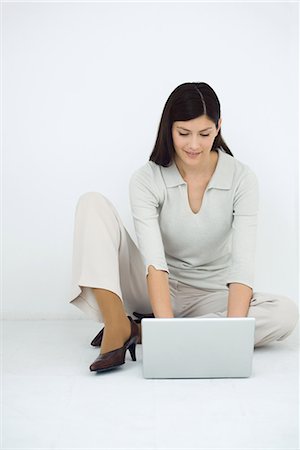 simsearch:633-02345800,k - Woman sitting on the ground, using laptop computer, smiling Stock Photo - Premium Royalty-Free, Code: 695-03379222