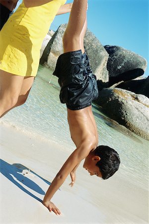 Woman helping boy do handstand on beach Stock Photo - Premium Royalty-Free, Code: 695-03379246