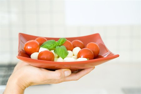 Woman's hand holding plate of tomato mozzarella salad Foto de stock - Sin royalties Premium, Código: 695-03379290