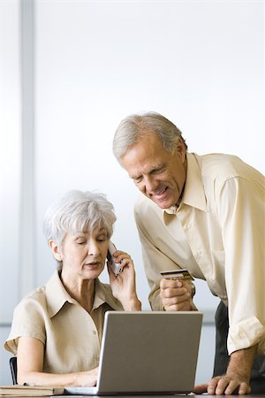debit card smile - Mature couple making credit card purchase, using laptop and cell phone Stock Photo - Premium Royalty-Free, Code: 695-03379309