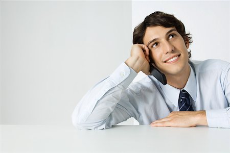 simsearch:695-03390134,k - Young man using cell phone, looking up, smiling Stock Photo - Premium Royalty-Free, Code: 695-03379385