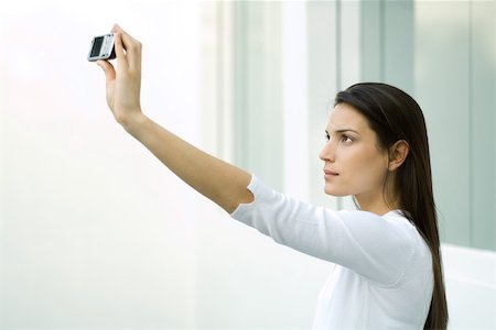 Woman photographing herself with photophone, arm raised Foto de stock - Sin royalties Premium, Código: 695-03379409