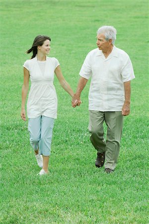 Grandfather and teen granddaughter walking outdoors, holding hands, smiling at each other Stock Photo - Premium Royalty-Free, Code: 695-03379435