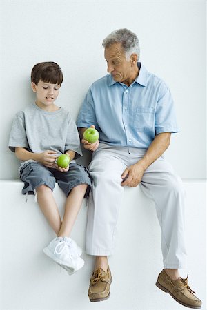 people with fruits cutout - Grandfather and grandson sitting together on ledge, both holding apples Stock Photo - Premium Royalty-Free, Code: 695-03379456