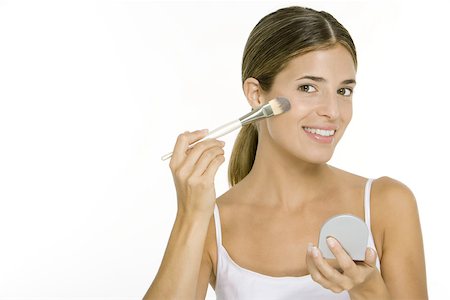 skin care routine - Woman applying blush, holding hand mirror, smiling at camera Stock Photo - Premium Royalty-Free, Code: 695-03379565