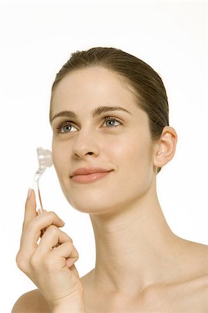 Woman using rollerball wand on cheek, smiling Stock Photo - Premium Royalty-Free, Code: 695-03379581