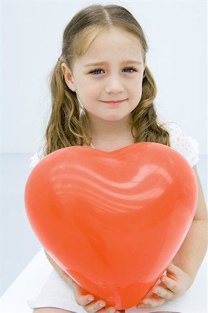red pigtails - Girl holding large balloon heart, smiling at camera, portrait Stock Photo - Premium Royalty-Free, Code: 695-03379608