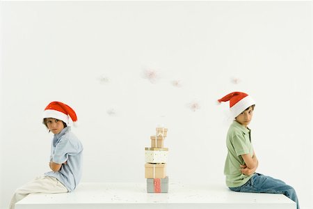 simsearch:695-03389917,k - Two brothers sitting back to back with arms folded, Christmas gifts stacked between them, one looking at camera Foto de stock - Royalty Free Premium, Número: 695-03379658