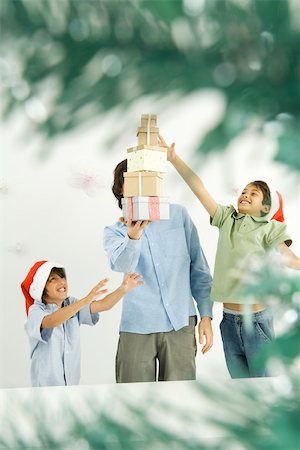 simsearch:632-06354048,k - Male holding stack of Christmas gifts, two boys reaching, viewed through Christmas tree branches Foto de stock - Sin royalties Premium, Código: 695-03379659
