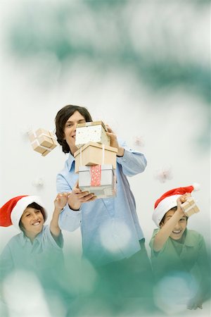 simsearch:632-06354048,k - Male carrying stack of Christmas gifts, boys reaching and scattering them, smiling Foto de stock - Sin royalties Premium, Código: 695-03379660
