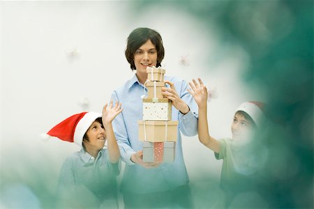 simsearch:632-06354048,k - Three brothers stacking Christmas gifts, smiling, selective focus Foto de stock - Sin royalties Premium, Código: 695-03379661