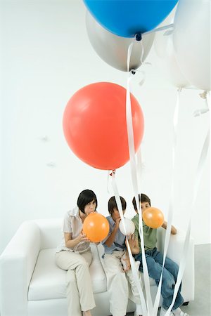 simsearch:649-07560319,k - Mother and two sons sitting on sofa, inflating balloons Stock Photo - Premium Royalty-Free, Code: 695-03379670