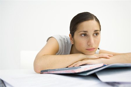 simsearch:632-03403385,k - Young woman sitting with notebook, head resting on arms, looking away Stock Photo - Premium Royalty-Free, Code: 695-03379696