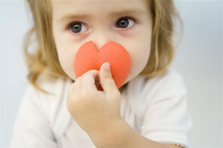 Little girl covering her nose with clown's nose, looking away, portrait Stock Photo - Premium Royalty-Free, Code: 695-03379697