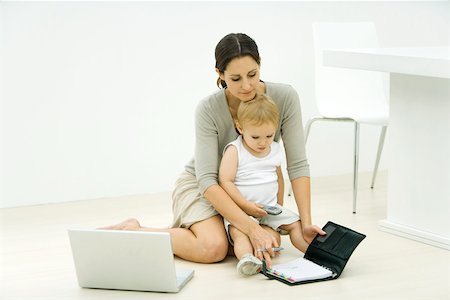 simsearch:695-03379718,k - Mother with toddler on lap, looking at agenda, laptop nearby Stock Photo - Premium Royalty-Free, Code: 695-03379716