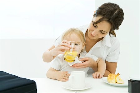 everyday family - Woman helping baby drink from glass of juice Stock Photo - Premium Royalty-Free, Code: 695-03379712