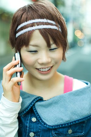 simsearch:632-01271142,k - Jeune femme japonaise à l'aide d'un téléphone cellulaire, souriant Photographie de stock - Premium Libres de Droits, Code: 695-03379778