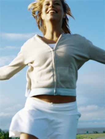 simsearch:633-01837186,k - Woman running outdoors in skirt and hooded sweatshirt, close-up, smiling Stock Photo - Premium Royalty-Free, Code: 695-03379815