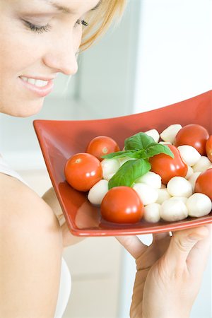 finger foods presentation - Woman holding up tomato mozzarella salad, smiling, cropped view Stock Photo - Premium Royalty-Free, Code: 695-03379848