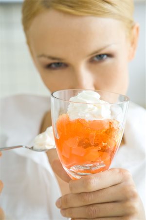 Woman holding up fruit dessert, looking at camera Stock Photo - Premium Royalty-Free, Code: 695-03379857