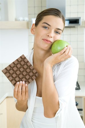 Woman holding large chocolate bar in one hand, apple in the other, smiling at camera Foto de stock - Sin royalties Premium, Código: 695-03379859