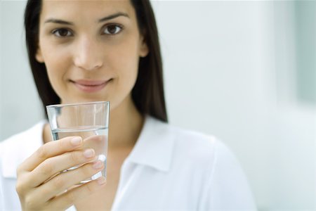 Woman holding glass of water, smiling at camera Stock Photo - Premium Royalty-Free, Code: 695-03379870