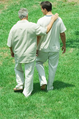 Mature man walking with arm around adult son's shoulder outdoors, rear view Stock Photo - Premium Royalty-Free, Code: 695-03379884