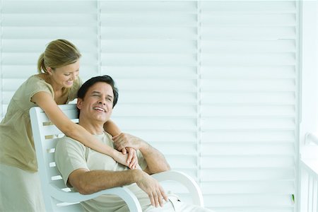 persiana - Man sitting in chair, woman standing behind, embracing, smiling Foto de stock - Sin royalties Premium, Código: 695-03379901