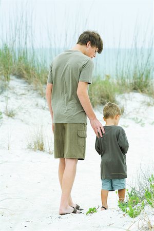 simsearch:841-06449859,k - Teen boy walking with little brother at the beach, rear view Foto de stock - Sin royalties Premium, Código: 695-03379902