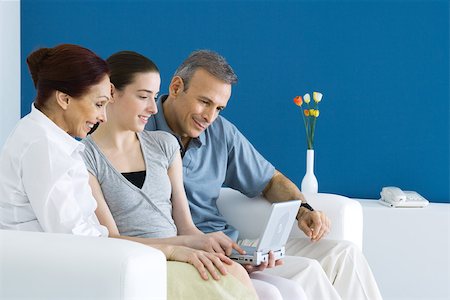 Family watching portable DVD player together on sofa Stock Photo - Premium Royalty-Free, Code: 695-03379958