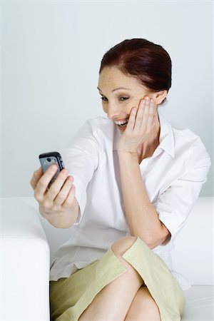 people shocked on phones - Woman taking photo of self with cell phone, smiling Stock Photo - Premium Royalty-Free, Code: 695-03379961