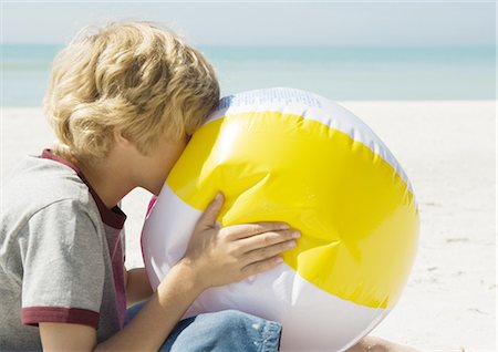 Boy blowing up beach ball Stock Photo - Premium Royalty-Free, Code: 695-03373391