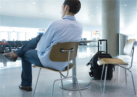 Man sitting in chair in airport, rear view Stock Photo - Premium Royalty-Free, Code: 695-03373805